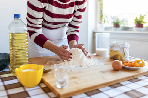 Frau macht Mehlhaufen auf Schneidebrett in Küche zu Hause - WPEF03987