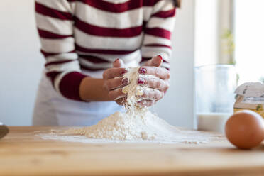 Mittlere erwachsene Frau mischt Mehl auf einem Schneidebrett für die Zubereitung in der Küche - WPEF03988