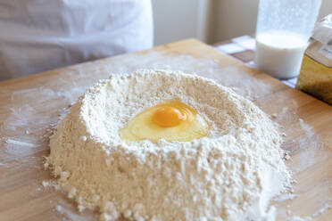 Egg in heap of flour on cutting board in kitchen - WPEF03990