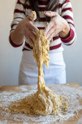 Mittlere erwachsene Frau knetet Teig bei der Zubereitung von Croissants in der Küche zu Hause - WPEF03997