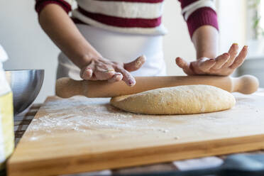 Frau bereitet Teig mit Nudelholz vor, um Croissants in der Küche herzustellen - WPEF04004