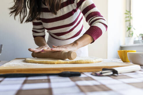 Frau glättet Teig mit Nudelholz, um Croissants in der Küche zu Hause zu machen - WPEF04006