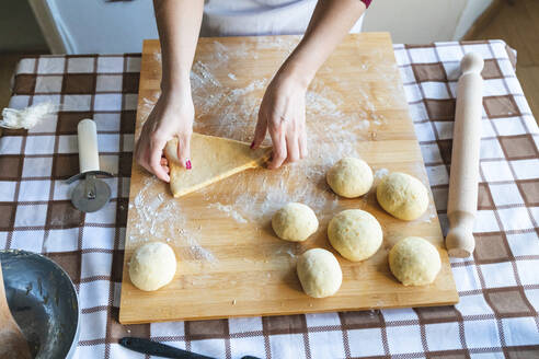 Frau macht Teigkugeln auf Schneidebrett, um Croissants in der Küche zu machen - WPEF04010