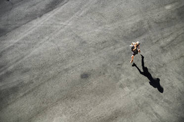 Frau läuft an einem sonnigen Tag auf der Straße - AZF00159