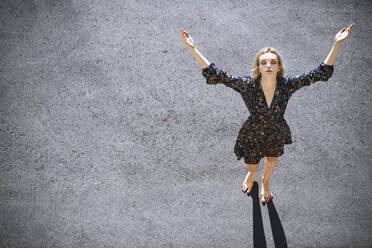 Young woman with arms raised standing on road - AZF00163