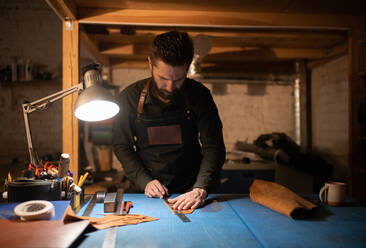 Bärtiger Handwerker misst Leder in der Werkstatt - CAVF92654