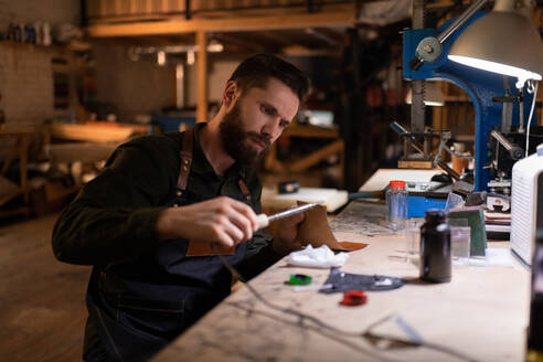 Fokussierter Handwerker mit Pyrographiemaschine auf Leder - CAVF92663