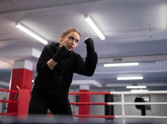 Female fighter practicing uppercuts on boxing ring - CAVF92673