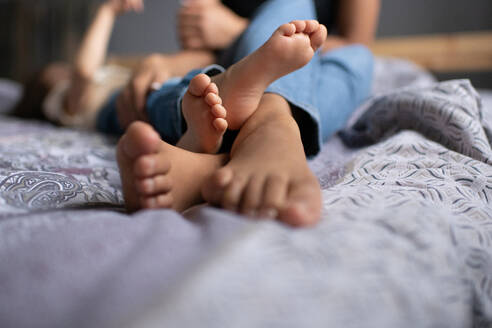 Cropped mother and child playing on bed - CAVF92688