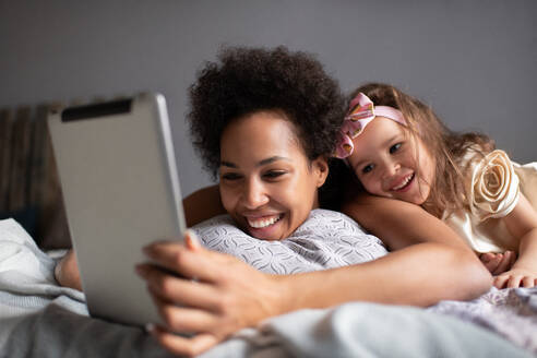 Gemischte Rasse Mutter und Tochter machen Videoanruf auf dem Bett - CAVF92690