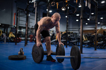 Muscular senior athlete preparing barbell for training - CAVF92694