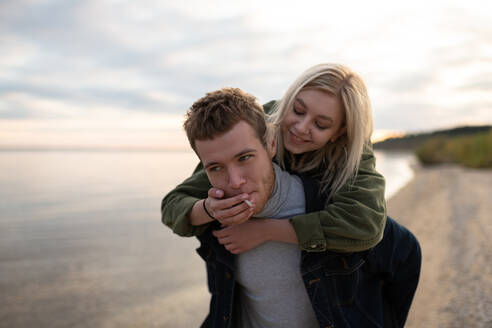 Smiling woman sharing cigarette to boyfriend near lake - CAVF92704