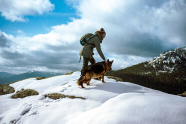 Young girl guiding a dog through the snow in the mountains on winter - CAVF92715