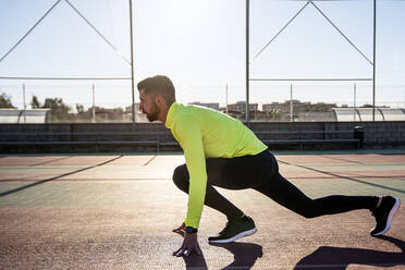 Männlicher Läufer beim Training auf dem Sportplatz an einem sonnigen Tag - AMPF00010