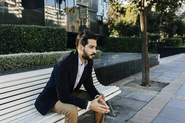 Thoughtful businessman looking away while sitting on bench - XLGF01127