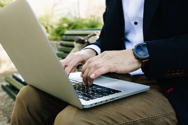 Businessman using laptop while sitting on bench - XLGF01156