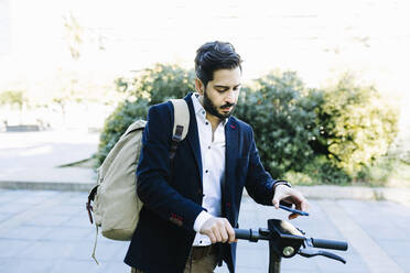 Mid adult businessman with backpack using mobile phone while standing by bicycle - XLGF01163