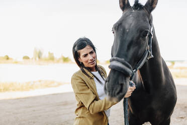 Woman with horse standing outdoors during sunny day - MRRF00871