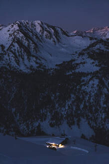 Beleuchtete Hütte am schneebedeckten Berg bei Sonnenaufgang - JAQF00258