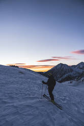 Älterer Mann Skifahren im Schnee gegen schneebedeckten Berg bei Sonnenaufgang - JAQF00263
