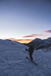 Mature man skiing in snow against snow covered mountain during sunrise - JAQF00263