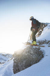 Männlicher Skifahrer auf einem Berggipfel bei Sonnenaufgang - JAQF00278