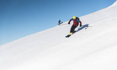 Älterer Mann beim Skifahren auf einem Berghang gegen den Himmel - JAQF00281