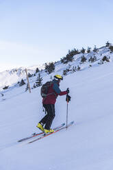 Älterer männlicher Skifahrer beim Klettern auf einem verschneiten Berg - JAQF00282