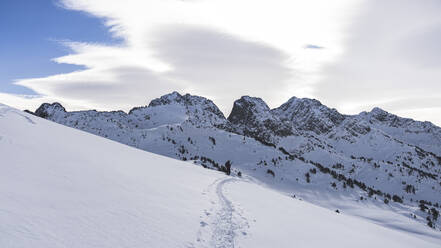 Männlicher Skifahrer auf der Piste eines verschneiten Berges vor bewölktem Himmel - JAQF00288