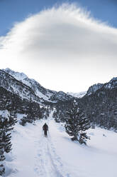 Männlicher Skifahrer auf einem schneebedeckten Berg vor bewölktem Himmel - JAQF00293