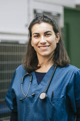 Smiling female veterinarian in blue uniform with stethoscope in hospital - DGOF01903