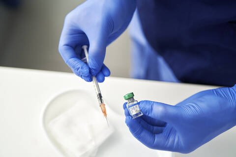 Hands holding Coronavirus vaccine and syringe stock photo