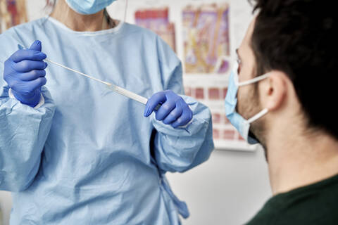 Medical professional with cotton swab for collecting sample of male patient stock photo