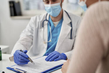 Männlicher Arzt erklärt einem Patienten in der Klinik die Behandlung - ABIF01356
