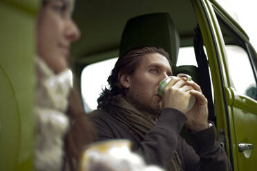 Young man drinking coffee while looking away
 - AJOF01002