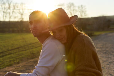 Woman embracing boyfriend from behind during sunset - VEGF03870