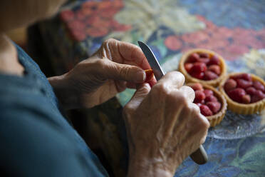 Ältere Frau bei der Zubereitung von Erdbeertörtchen - MAMF01626