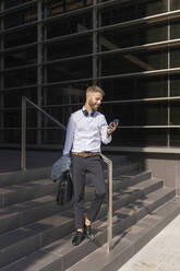 Mid adult businessman using mobile phone while standing on steps - BOYF01783