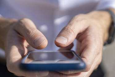 Close-up of businessman using smart phone while standing outdoors - BOYF01801