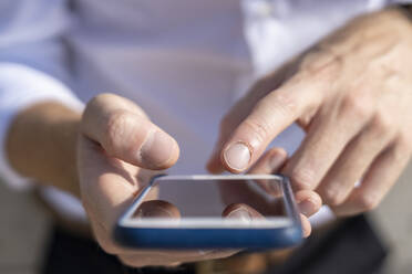 Businessman using smart phone outdoors during sunny day - BOYF01802