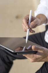 Businessman working on digital tablet while sitting outdoors - BOYF01821