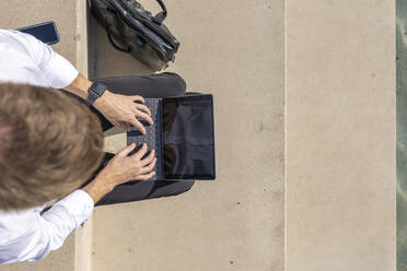 Unternehmer, der ein digitales Tablet benutzt, während er auf einer Treppe sitzt - BOYF01830