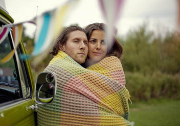 Junger Mann und Frau in Decke eingewickelt, die sich umarmen - AJOF01018