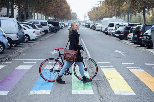 Frau mit Fahrrad, die auf einem Zebrastreifen geht und wegschaut - JSRF01397