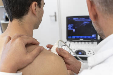 A doctor performs an ultrasound on a patient's shoulder - CAVF92809