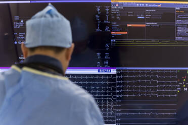 An angiologist sits in front of a screen showing a patient's heartbeat - CAVF92890