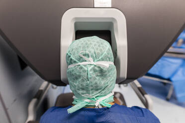 Ein Chirurg steht vor der Steuerung eines Roboters im Operationssaal - CAVF92891