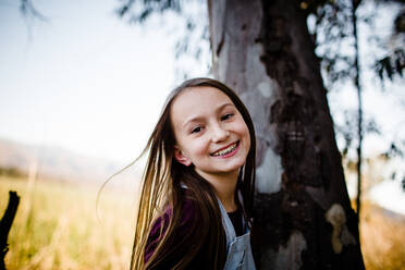 Junges Mädchen lächelt für die Kamera neben einem Baum - CAVF92938