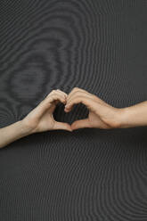 Studio shot of male and female hand making heart shape - PSTF00870