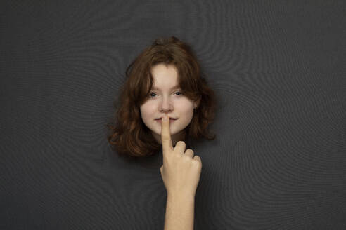 Studio shot of head of teenage girl shushed by male hand - PSTF00875